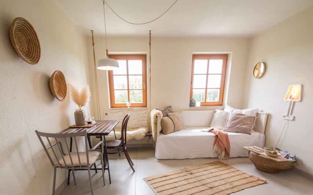 Wohn- und Esszimmer mit Daybed und Kissen und Esstisch mit zwei Stühlen